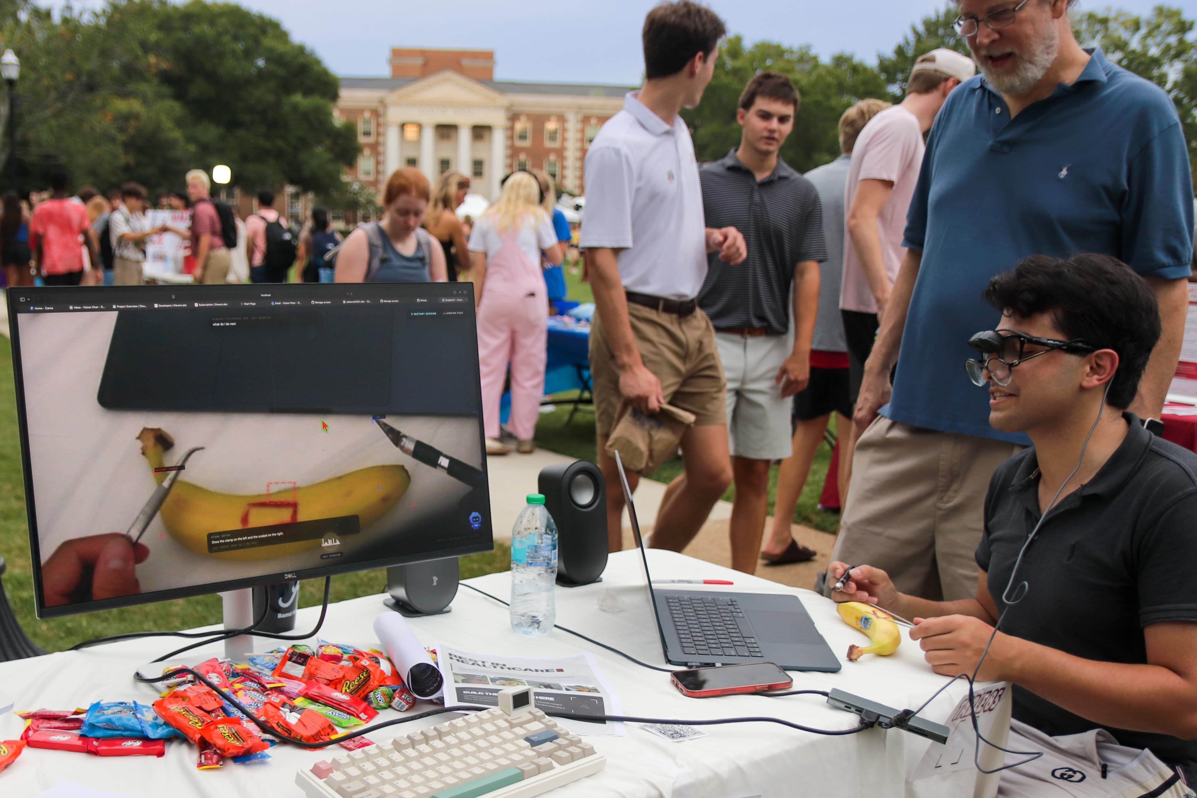 Faizan demonstrating a project outdoors at a campus table.